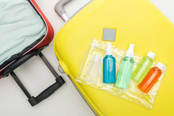 Kozmetik çantanın en üst görüntüsü ve seyahat çantasında sıvı bulunan şişeler. - Fotoğraf, Görsel