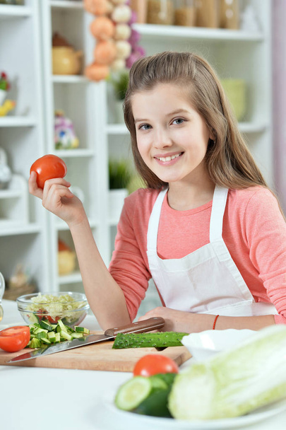 attractive young girl holding tomato in the kitchen - Фото, зображення