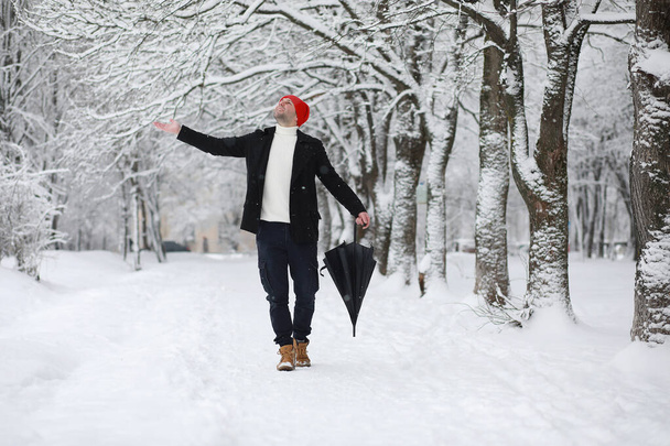 A man on a walk in the park. Young man with in the winter snowfa - Foto, imagen
