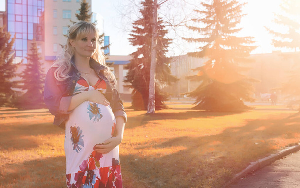 公園での散歩に妊娠中の女の子。Ci の腹を持つ少女 - 写真・画像