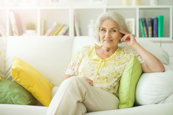 Beautiful senior woman sitting on sofa at home - Photo, Image