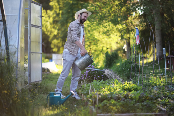 Mann Bauer gießt einen Gemüsegarten - Foto, Bild