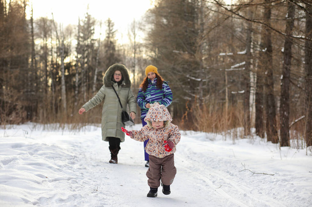 Çocuk kış parkında koşuyor ve ailesiyle eğleniyor. - Fotoğraf, Görsel