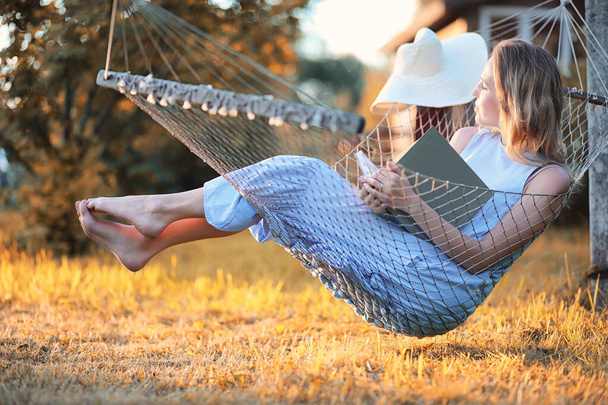 Beautiful girl in hammock reading a book  - Фото, изображение