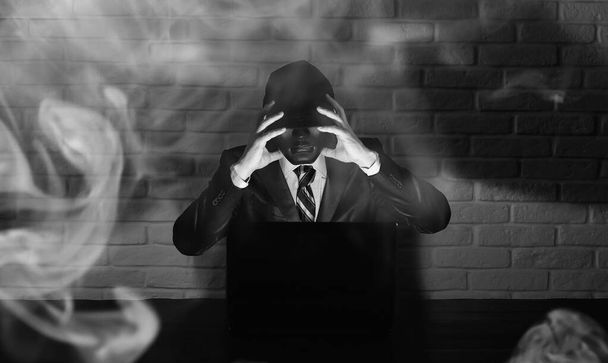Hacker in black mask and hood at the table - Foto, imagen