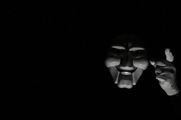 Bílá strašidelná maska na černém pozadí s bílou rukou. - Fotografie, Obrázek