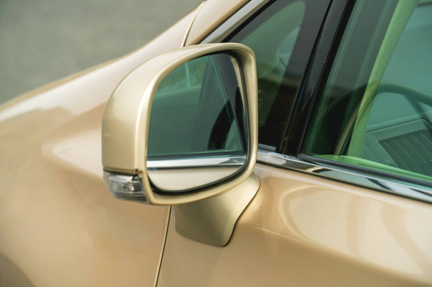 Photo of rear-view side mirror on a gold-coloured car - Fotografie, Obrázek