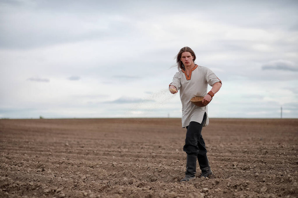 Un giovane contadino semina il campo con il grano
 - Foto, immagini