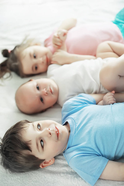 Les enfants s'allongent sur le lit à côté du nouveau-né, petite sœur
. - Photo, image