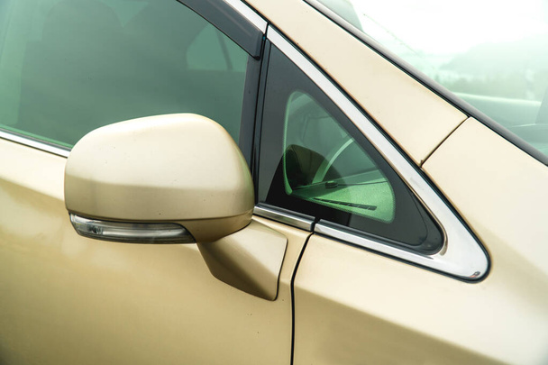 Photo of rear-view side mirror on a gold-coloured car - Foto, afbeelding