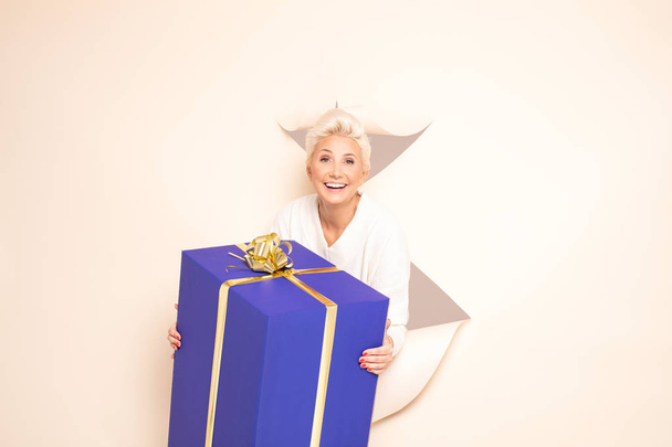 Smiling lady holding big gift. - Foto, afbeelding