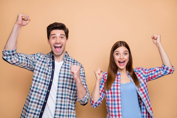 Portrait of his he her she nice attractive lovely charming cheerful cheery couple team wearing checked shirt celebrating great luck isolated over beige pastel color background - Fotografie, Obrázek
