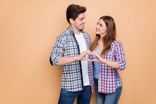 Portrait of his he her she nice attractive lovely tender sweet gentle cheerful couple wearing checked shirt showing heart figure honey moon isolated over beige pastel color background - Φωτογραφία, εικόνα