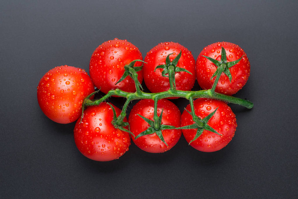 Όμορφες κόκκινες ντομάτες με σταγόνες σε μαύρο φόντο. - Φωτογραφία, εικόνα
