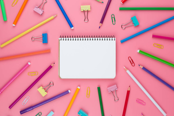 Színes tanszerek egy papírt rózsaszín háttér helyét a szöveget. Különböző színű írószerek. Vissza az iskolai koncepcióhoz. - Fotó, kép