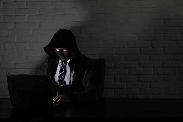 Haker w czarna maska i kaptur na stole - Zdjęcie, obraz