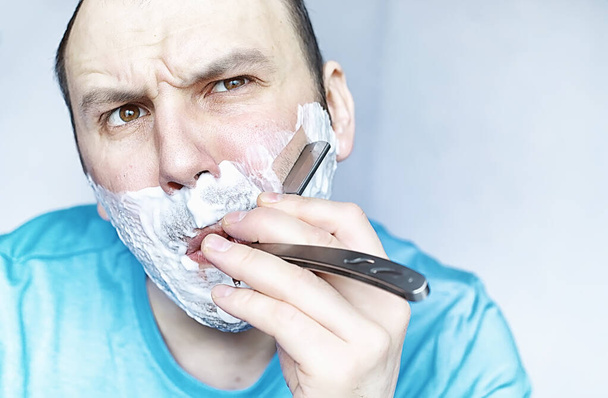 Ein Mann rasiert sich vor einem Spiegel. Rasierschaum. Einweg-Rasiermesser. - Foto, Bild