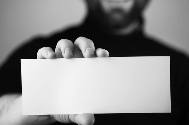 mały biały kawałek papieru w jego ręce człowiek monochromatyczny - Zdjęcie, obraz