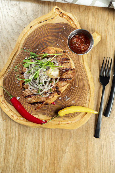 Top view tasty Grilled Pork neck served on pita bread with onion, microgreen and hot pepper. Wooden background. Copy space. Selective focus - Foto, Imagem