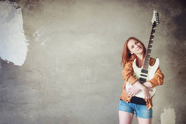 Νεαρή κοκκινομάλλα κοπέλα με μια ηλεκτρική κιθάρα. Gir μουσικός βράχου - Φωτογραφία, εικόνα
