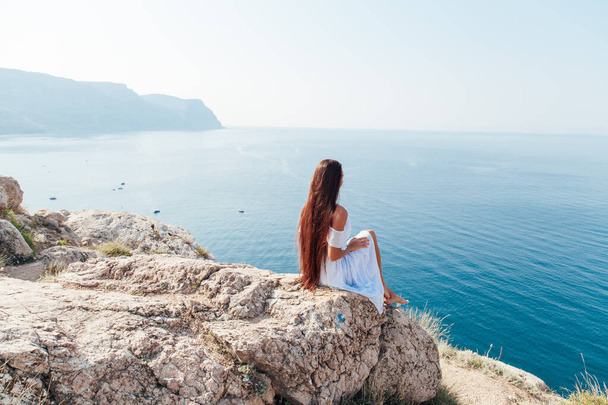 portré egy gyönyörű nő hosszú haj egy hegyen, kilátással a tengerre - Fotó, kép