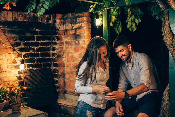 young couple using smartphone outdoor in backyard - Photo, image