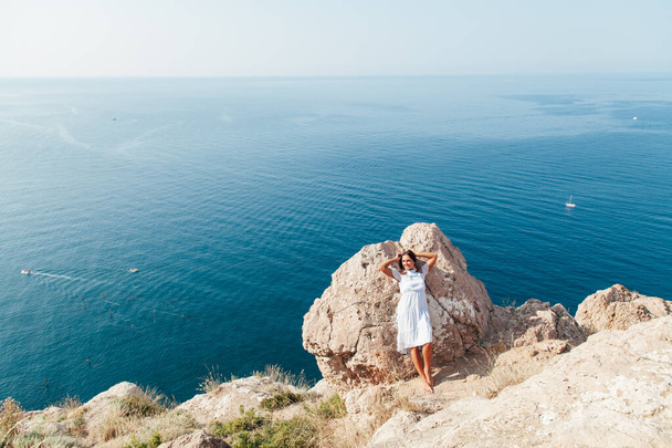 Porträt einer schönen Frau mit langen Haaren auf einem Berg mit Blick auf das Meer - Foto, Bild