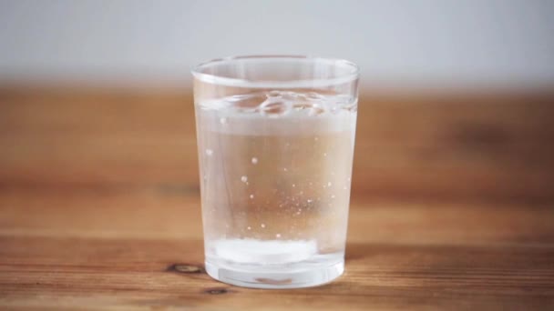 effervescent pill dropping into glass of water - Filmati, video