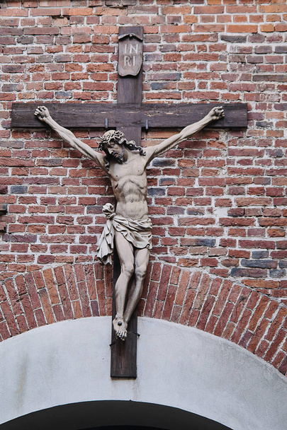 Pequena estátua de Jesus Cristo crucificado na fachada da igreja
 - Foto, Imagem