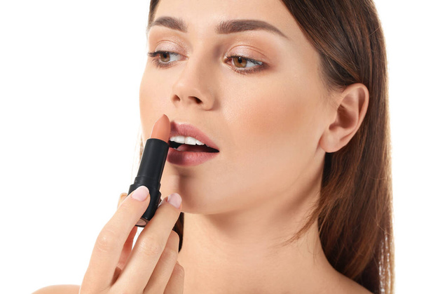 Mooie jonge vrouw aanbrengen van Lipstick tegen witte achtergrond - Foto, afbeelding