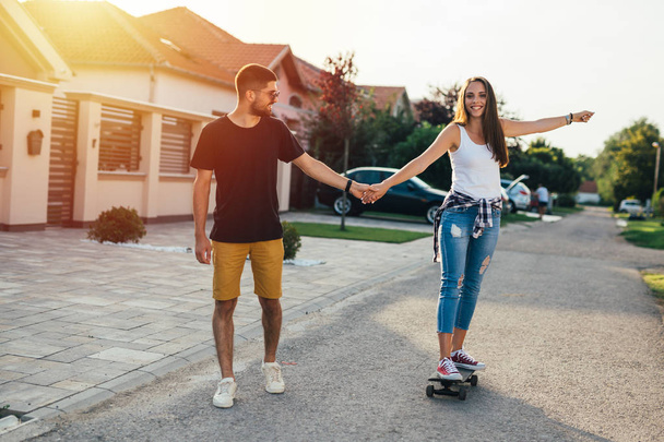 fancy happy couple driving skateboard outdoor - Foto, afbeelding