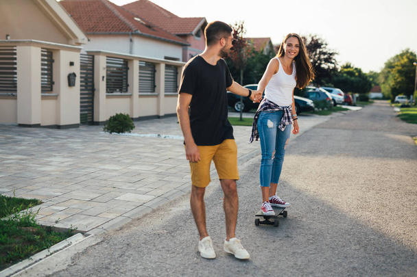 fancy happy couple driving skateboard outdoor - Photo, image