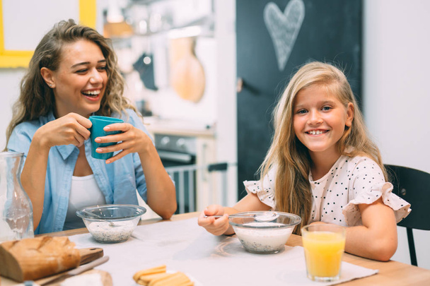Family time at home. Cheerful mother and daughter having breakfast. - Photo, Image
