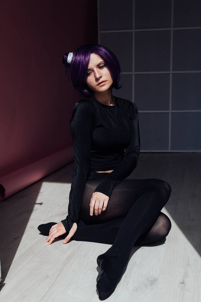 紫の髪の女の子は黒い服で床に座っている - 写真・画像