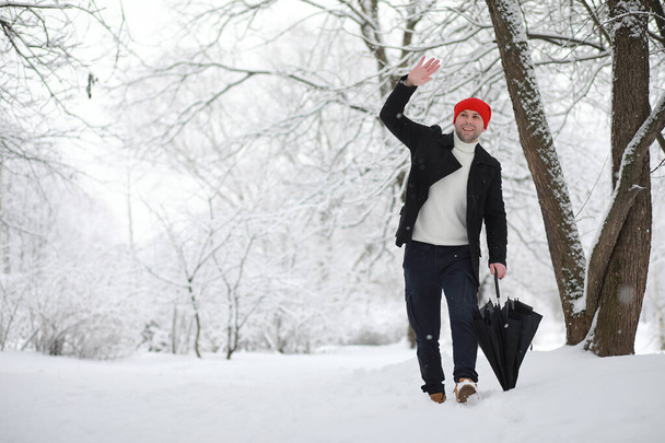 Parkta yürüyen bir adam. Genç adam kışın karla kaplı - Fotoğraf, Görsel