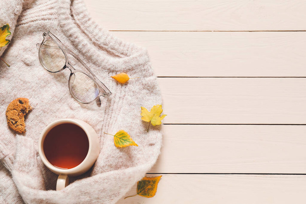 Красивая осенняя композиция с теплым свитером и чашкой чая на деревянном фоне
 - Фото, изображение