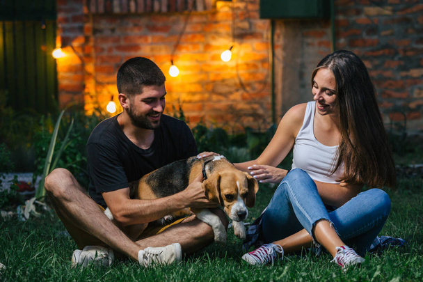 young couple playing with dog in home backyard - Valokuva, kuva
