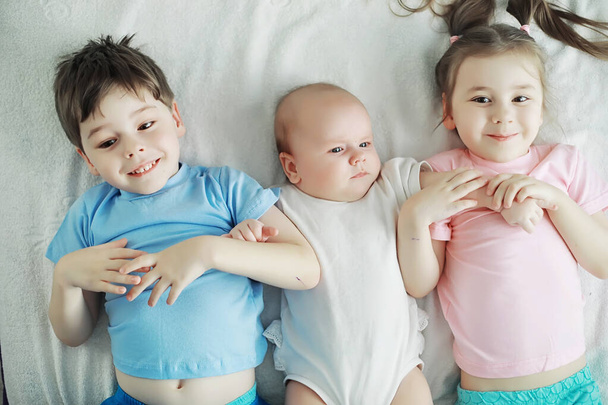 I bambini si trovano sul letto accanto al neonato, sorellina.
. - Foto, immagini