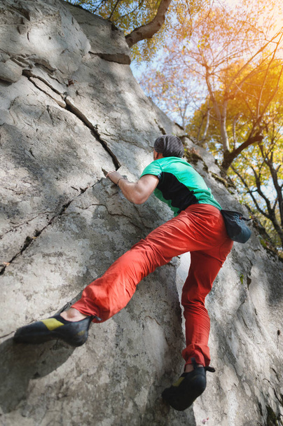 Um alpinista de idade livre está pendurado em uma parede de rocha em uma floresta nas montanhas. Conceito de Desporto Maduro - Foto, Imagem