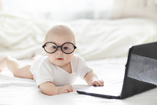 Un neonato è sdraiato su un letto morbido in occhiali
. - Foto, immagini