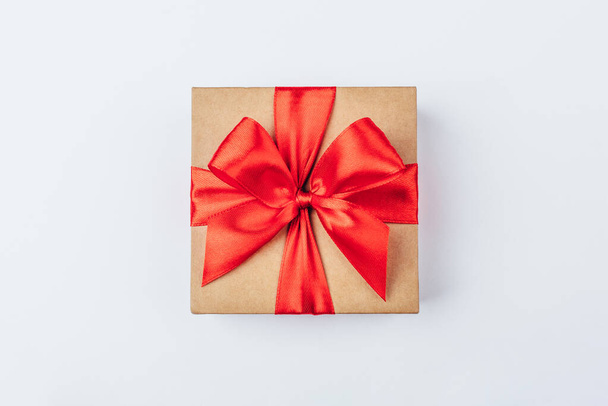 Cardboard gift box with red bow on white background. - Fotografie, Obrázek