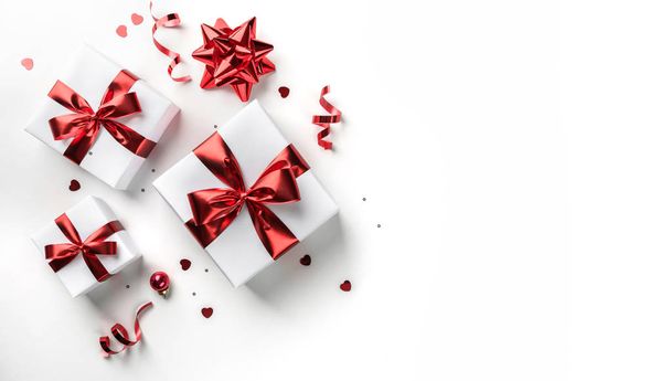 Caixas de presente de Natal com fita vermelha, brilhos, confetes e decoração em fundo branco. Natal e Feliz Ano Novo. Deitado plano, vista superior - Foto, Imagem