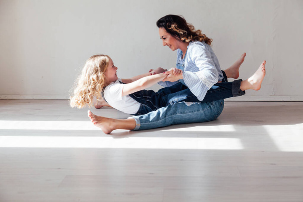 Mom and daughter in jeans sit together cuddling - Foto, imagen