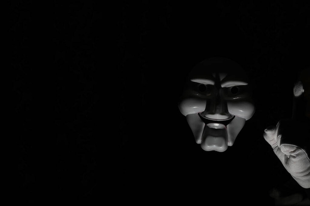 Máscara assustadora branca em um fundo preto com mão branca
. - Foto, Imagem