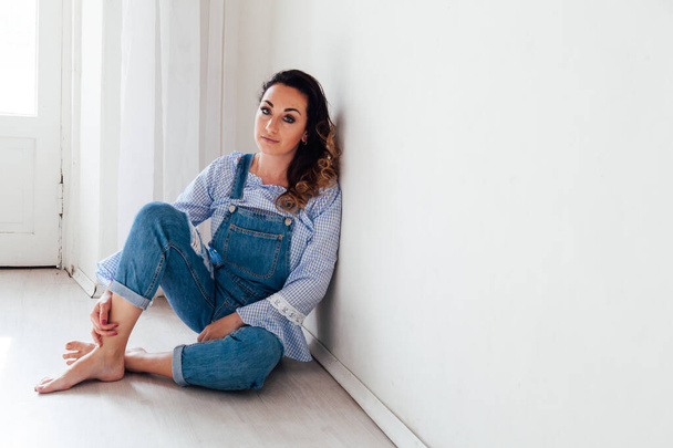 Portrait of a beautiful woman in a denim jumpsuit at home - Foto, afbeelding