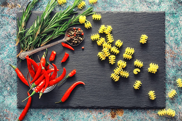 Ongekookte pasta op een stenen achtergrond. Met kruiden en specerijen - Foto, afbeelding