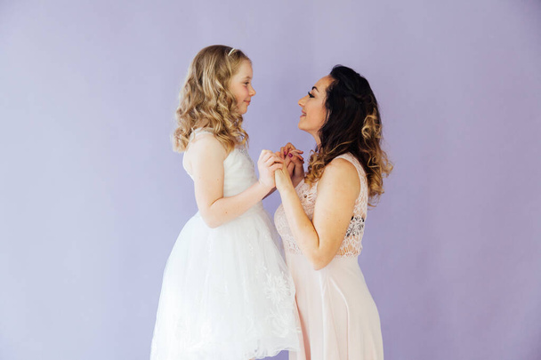 Mom and daughter in white dresses hold hands - Photo, image