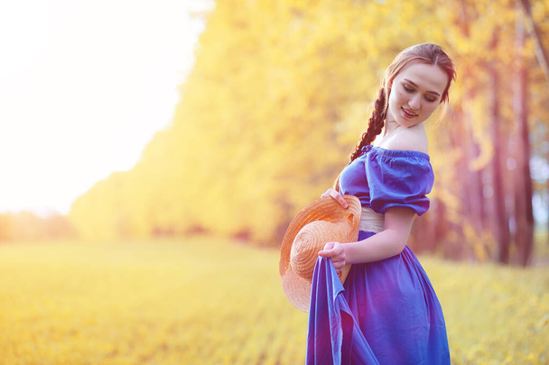 Young beautiful girl in dresses on nature. A girl in a hat walks - Photo, Image