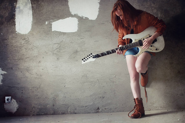 Νεαρή κοκκινομάλλα κοπέλα με μια ηλεκτρική κιθάρα. Gir μουσικός βράχου - Φωτογραφία, εικόνα
