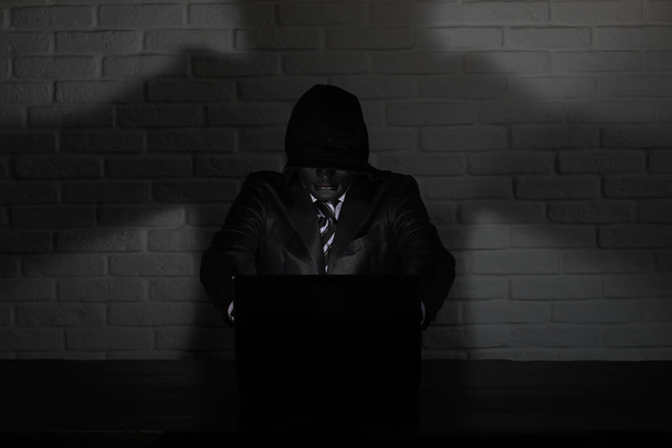 Hacker v černou masku a kapuce u stolu - Fotografie, Obrázek